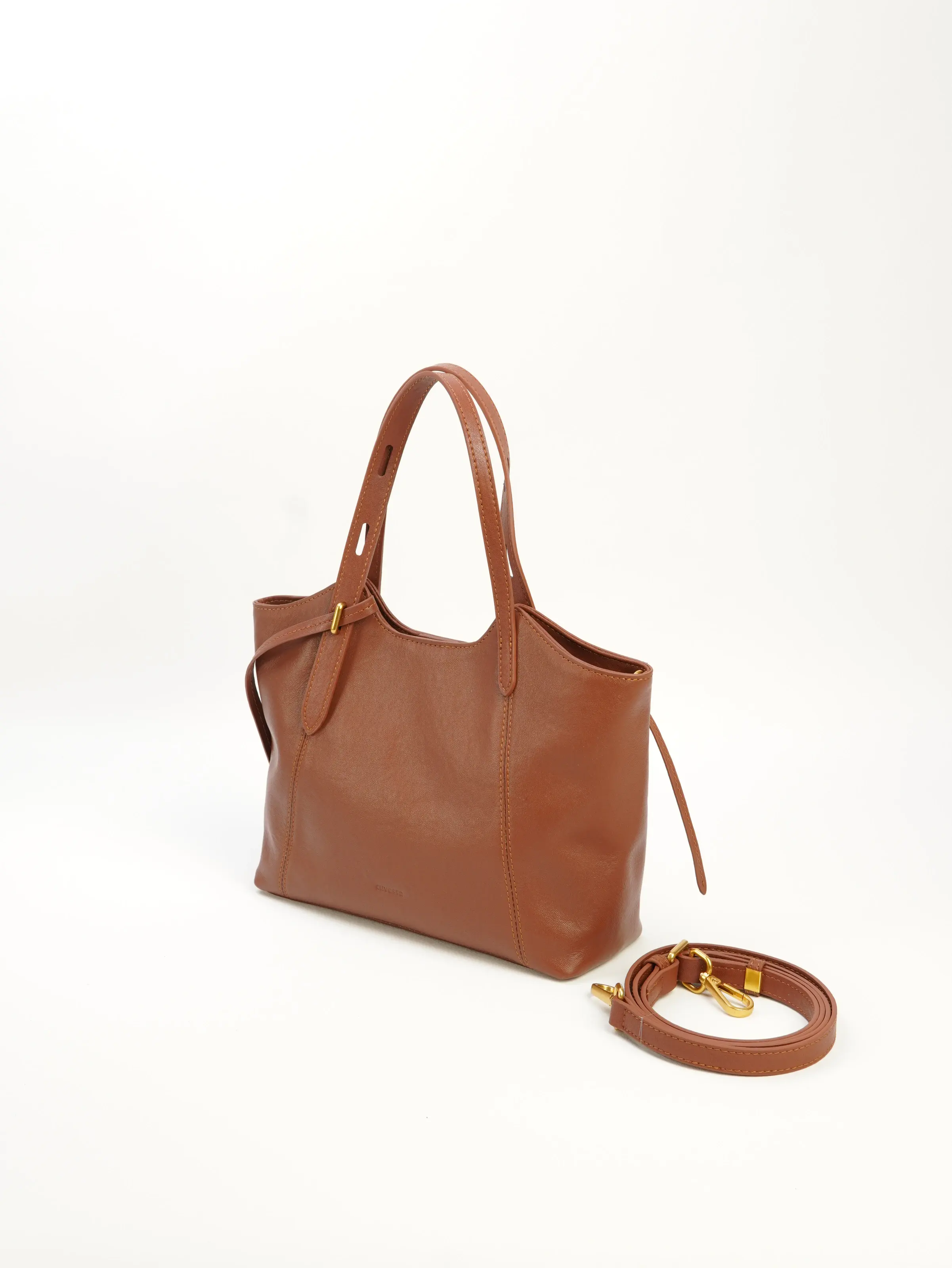 Nora cognac tote bag at an angle with a longer strap photographed beside it