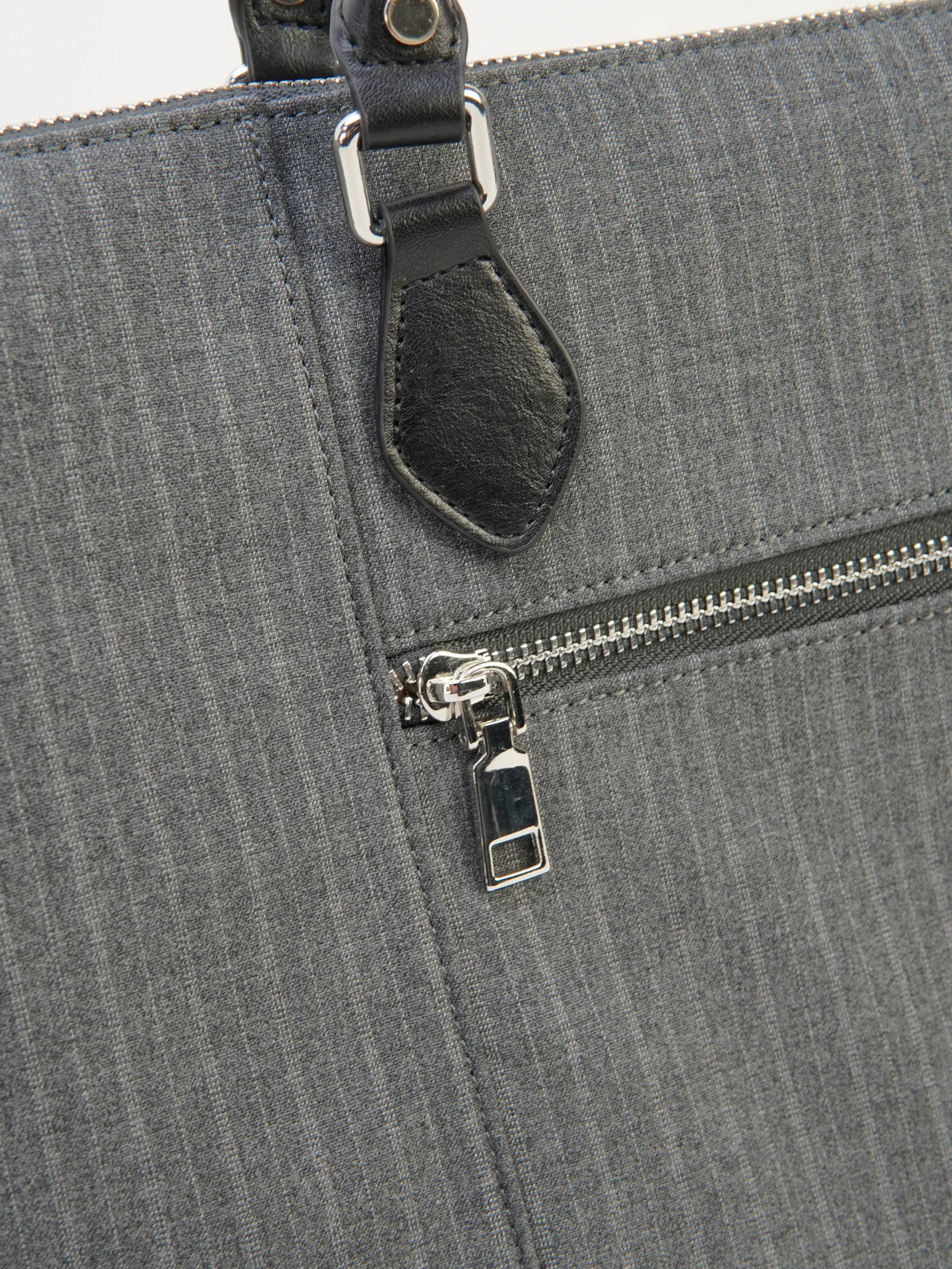 Close view of Ellis exterior zip pocket and textured gray surface