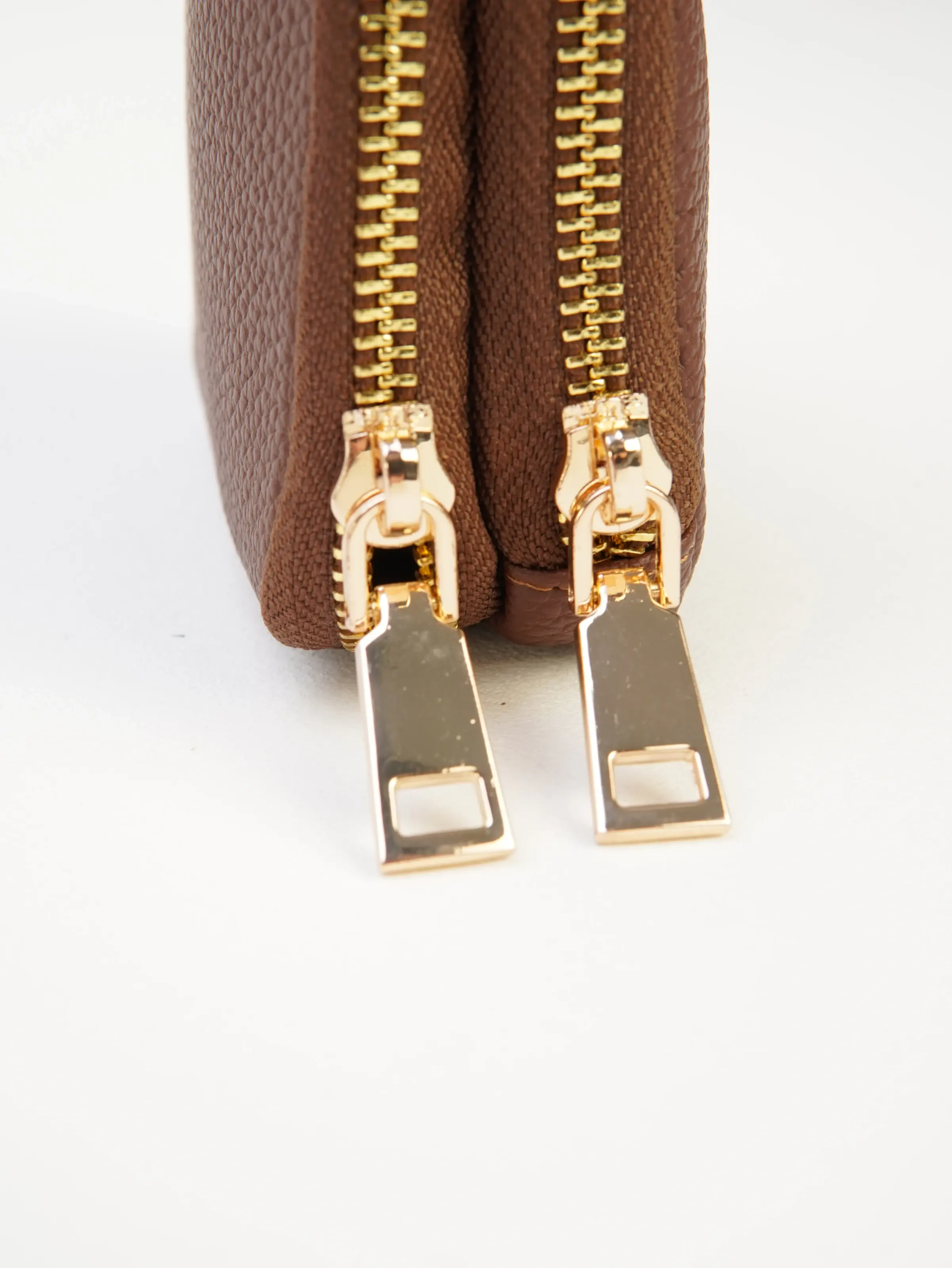 Close view of the two gold-tone zipper pulls on the Nia cocoa jewelry case