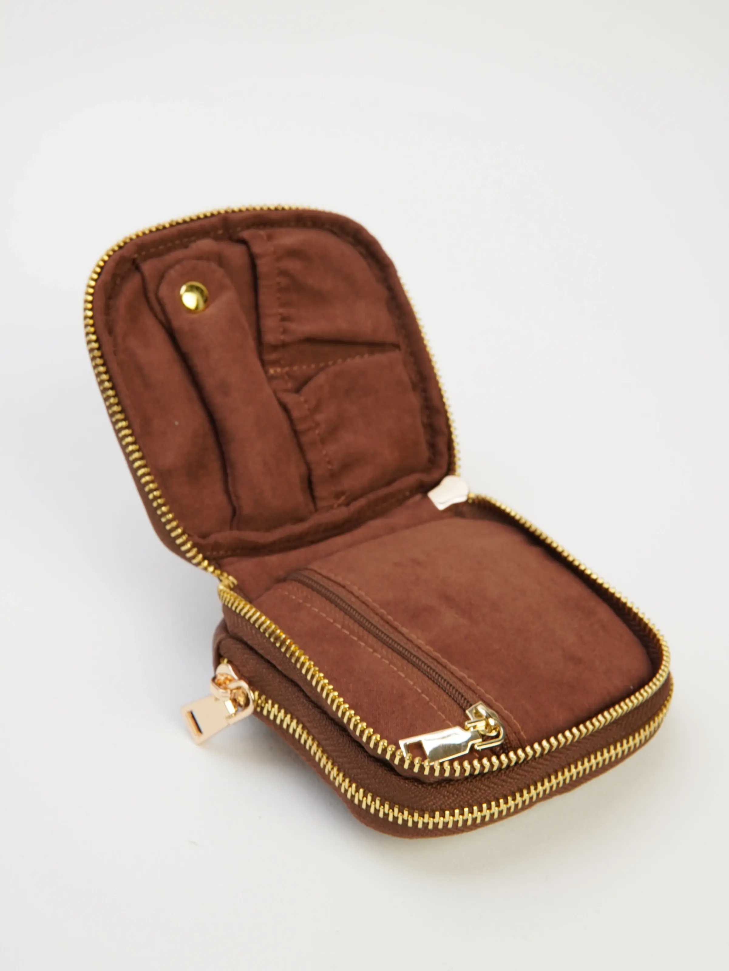 Open Nia cocoa jewelry case showing a zip section and small interior compartments